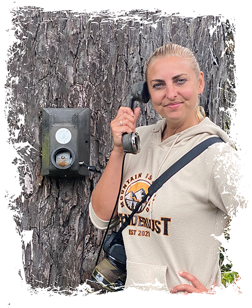 Woman holding an old fashioned telephone attached to a tree