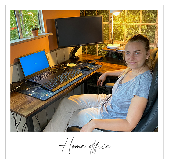 Young woman sitting at a desk with computers in a home office setting