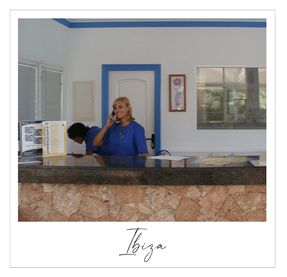 Young blond woman dressed smartly in blue answering the phone at a hotel reception