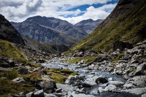 A rocky stream flowing through a valley towards mountains in the background